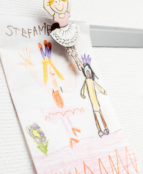 Kinderzeichnung mit Magneten an weißer Tafel befestigt.